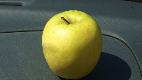 Ein glänzender grüner Apfel steht auf dem Armaturenbrett eines Autos, um den Geruch von kaltem Zigarettenrauch zu neutralisieren.