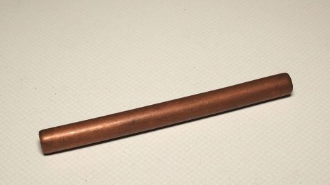 Angelaufene Gefäße, Armreifen, Anhänger etc. aus Kupfer, werden wieder schön mit Zahnpasta. Ein glänzendes Kupferobjekt liegt auf einer neutralen Oberfläche, ideal zur Anwendung von Zahnpasta zur Reinigung.