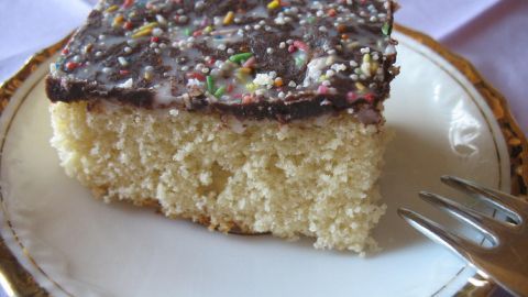 Ein Stück Hirschhornkuchen wie von Oma liegt auf einem Teller, mit hellem Teig und bunten Streuseln.