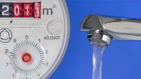 Ein Wasserhahn mit fließendem Wasser neben einem Wasserzähler, der den Wasserverbrauch anzeigt und zum Wassersparen anregt.