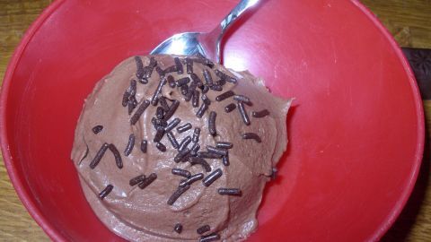 Ein Schokoladen-Sorbet befindet sich in einer roten Schüssel, garniert mit Schokoladenspänen, bereit zum Genießen.