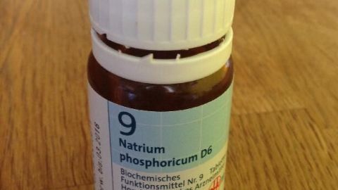 Ein Fläschchen mit „Natrium phosphoricum D6“ steht auf einem Holztisch, um Krankheiten wie Durchfall bei Hunden zu behandeln.