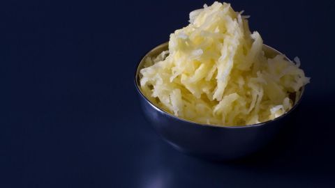 Eine Schüssel mit lockerem, cremigem Buttermilch-Götze auf einem dunklen Tisch steht im Mittelpunkt der Aufnahme.