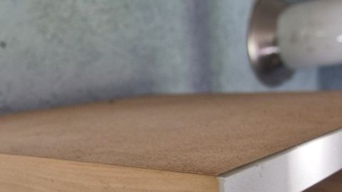 Auf einem Küchenschrank zeigt sich eine glatte Oberfläche, die keinen Fettstaub aufweist, neben einer Abzugshaube im Hintergrund.