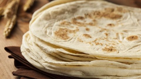 Tortilla Wraps liegen gestapelt auf einem Holzbrett, bereit für die Zubereitung von Flammkuchen in der Küche.