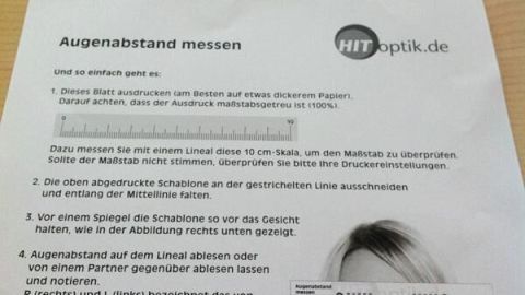 Ein Papiertool zum Messen des Augenabstands liegt auf einem Tisch, um das Bestellen von Brillen zu erleichtern.