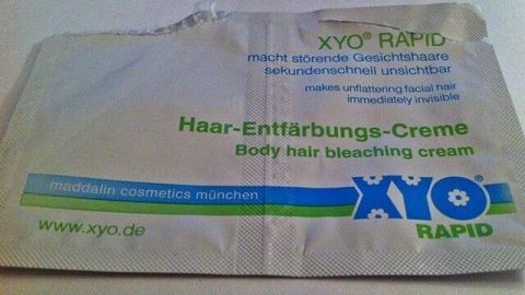 Eine Tube Haar-Entfärbungs-Creme liegt flach auf einer Oberfläche, bereit zur Anwendung für störende Gesichtshaare.