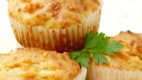 Drei würzige Gemüse-Muffins stehen auf einem Holzbrett, dekoriert mit frischem Koriander, appetitlich angerichtet.