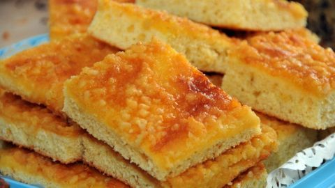 Mehrere Stücke Kokosblechkuchen liegen gestapelt auf einem blauen Tablett in einem festlichen Ambiente.