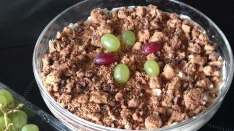 Cookies mit Weintrauben sind in einer Schüssel. Sie liegen auf einer glatten Oberfläche, daneben frische Weintrauben.