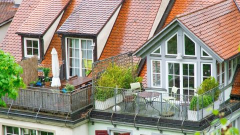 Ein Balkon mit Pflanzen und einem Sonnenschirm schützt vor neugierigen Nachbarn in einem urbanen Wohnumfeld.