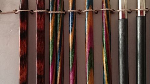 Eckige Stricknadeln sind ordentlich aufgereiht und zeigen verschiedene Farben und Größen für das Stricken.