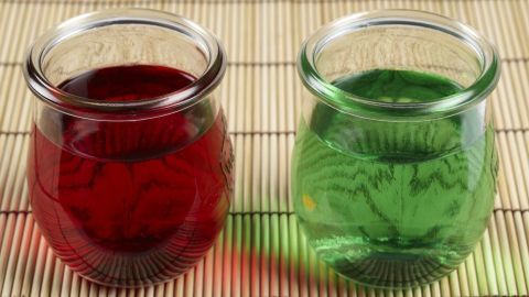 Zwei Gläser mit roter und grüner Götterspeise stehen auf einem Bambusuntergrund und warten auf die Zubereitung.