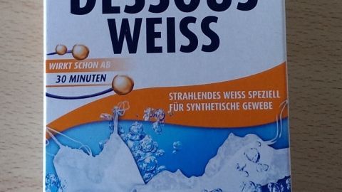 Eine Verpackung von Heitmann mit der Aufschrift "Dessous Weiß" zeigt ein Produkt zur Entfernung von Grauschleiern in Wäsche.