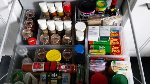 Eine Gewürzschublade nach Maß zeigt ordentlich angeordnete Gewürze und Saucen in transparenten Boxen, bereit zur Nutzung.