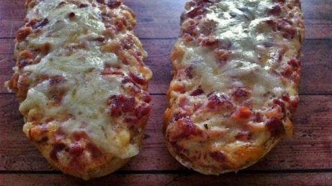 Herzhafte Ofen-Brötchen liegen goldbraun auf einem Holzbrett, mit geschmolzenem Käse und würziger Füllung.