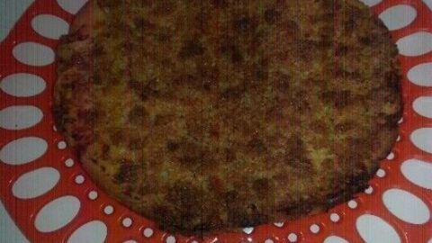 Prasselkuchen auf rotem, verziertem Teller präsentiert in schlichtem, hellem Umfeld.