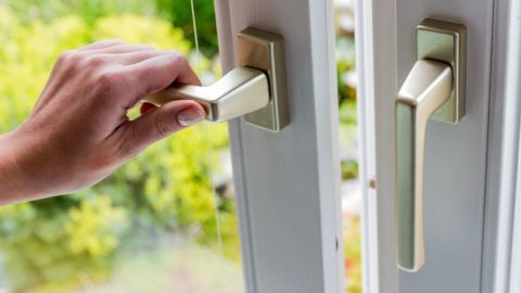 Eine Hand öffnet ein Fenster, um frische Luft hereinzulassen, was zur optimalen Luftfeuchtigkeit in Wohnräumen beiträgt.