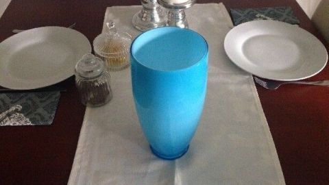 Eine blaue Vase steht als Tischabfallbehälter auf einem Tisch, umgeben von Tellern und Kerzen, im Essbereich.