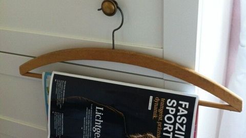 Ein Kleiderbügel hält eine Zeitung, die an einem Schrank hängt, während der Raum hell und freundlich wirkt.