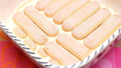 Löffelbiskuit liegen in einer Schüssel mit einer Quark-Joghurtcreme, bereit für ein Dessert mit Pfirsichen.