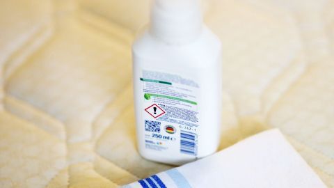 Eine Flasche mit Reinigungsmittel steht auf einer Matratze, während ein Handtuch bereitliegt, um Blutflecken zu entfernen.