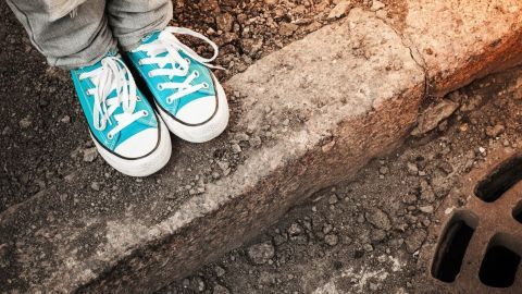 Türkise Schuhe stehen auf einer Betonkante, während der Schmutz um die Füße herum sichtbar ist, was die Reinigung erforderlich macht.