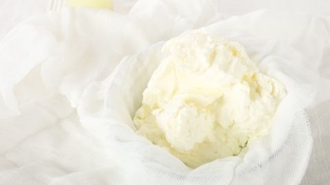 Quark liegt frisch und cremig in einem Käsetuch, bereit zur Verwendung in einem hellen Küchenumfeld.