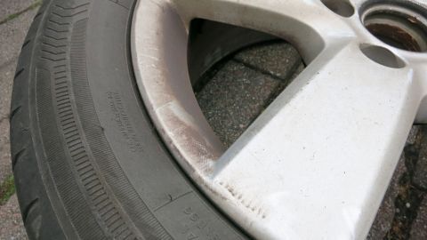 Alufelge mit Flecken, die auf einem grauen Untergrund gereinigt werden soll, um den Glanz zurückzugewinnen.