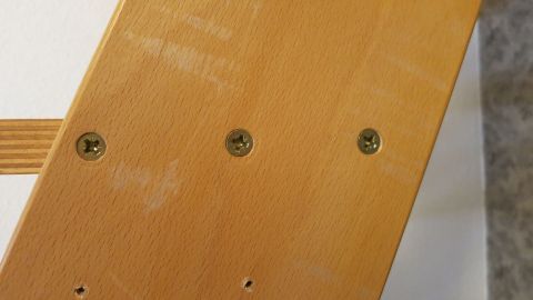 Ein tief, in das durchgedrehte Bohrloch gestecktes Streichholz sorgt für neuen Halt der Schraube! Holzschrauben sind lose in einem Holzstück. Eine Person nutzt ein Streichholz, um sie wieder festzuziehen.