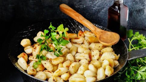 In einer Pfanne braten goldene Gnocchi mit frischer Petersilie, um eine einfache Beilage für jedes Gericht zu kreieren.