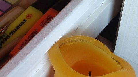 Eine gelbe Kerze liegt an einer Schublade, die sich schwer öffnen lässt, um das Problem der klemmenden Schubladen zu lösen.