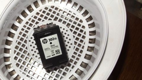Ein Ultraschallbad kann Druckköpfe effektiv reinigen, wie hier im Bild mit einer HP 302XL Patrone gezeigt. Durch die sanften Ultraschallwellen werden Tintenreste entfernt und die Lebensdauer der Patrone verlängert. Ein HP 302XL Tintenpatrone liegt in einem weißen Gitterkorb eines Ultraschallbads, bereit zur Reinigung.