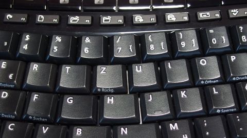 Eine verschmutzte Tastatur liegt vor, während jemand reinigt, um Schmutz und Staub zu entfernen.