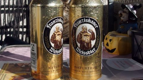 Zwei goldene Bierdosen stehen nebeneinander auf einem Tisch, ideal um beim Grillen oder Picknick zu kühlen und zu genießen.