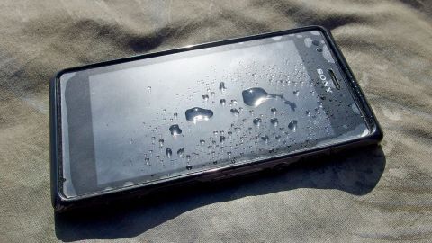 Ein nasses Handy liegt auf einer Oberfläche, mit Wassertröpfchen darauf, das auf eine mögliche Beschädigung hindeutet.