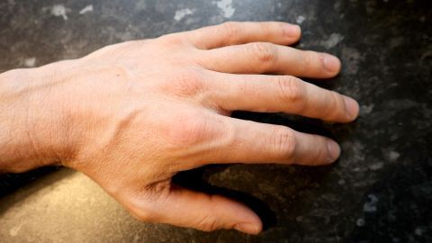 Ein männlicher Hand liegt sanft auf einer dunklen, glatten Oberfläche und vermittelt den Eindruck von Butterweiche.