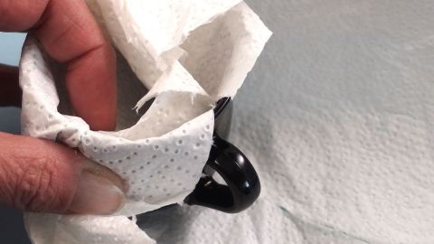 Ein Handgriff hält ein zerbrechliches Glasobjekt, das in ein Tuch eingewickelt ist, um es umzugsgerecht zu verpacken.