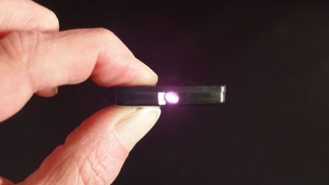 Eine Hand hält eine Fernbedienung mit leuchtendem Punkt, um zu zeigen, dass sie möglicherweise defekt ist.