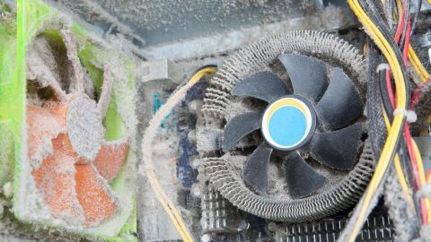 Ein PC-Lüfter ist stark verstaubt und dreht sich, während er in einem Computergehäuse steht. Staubpartikel sind sichtbar.