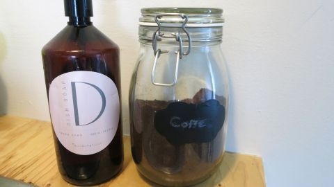 Eine Flasche mit Seife und ein Glas mit Kaffeesatz stehen auf einem Regal, um ölverschmierte Hände zu reinigen.