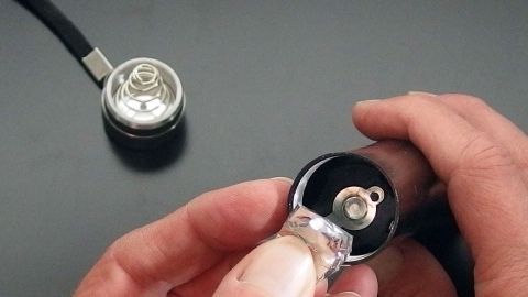 Schlechte Kontakte von Batterien beseitigen: Ein kleines Stückchen Alufolie klein gefaltet und zwischen die Kontakte geklemmt, kann da Abhilfe schaffen. Eine Person hält eine Batterie mit einer Alufolie, um die Kontakte zu verbessern; im Hintergrund ist eine zweite Batterie sichtbar.