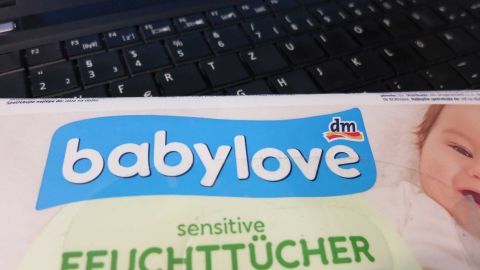 Babyfeuchttücher kann man individuell zweckentfremden: U. a. werden verschmutzte Tatstaturen damit ratzfatz sauber. Die Babyfeuchttücher von DM liegen vor einer schmutzigen Tastatur, bereit zur Reinigung der Verschmutzungen.