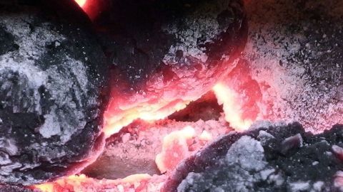 Glühende Holzkohle liegt nah beieinander und erzeugt intensive Hitze, bereit zum Grillen in einer gemütlichen Umgebung.