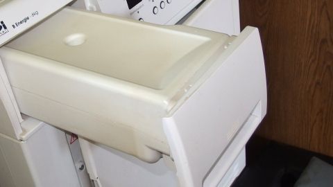 Wäschetrocknerwasser eignet sich sehr gut als Scheibenwasser für die Scheibenwaschanlage im Auto. Ein Wäschetrockner mit einem herausziehbaren Behälter für Wasser steht in einer Küche. Der Behälter ist leer.