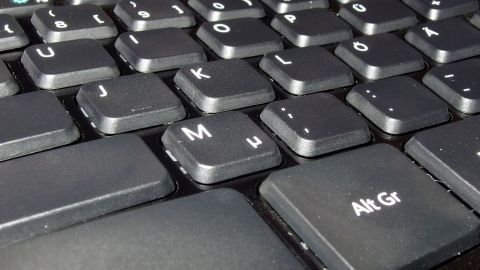 Mit einem in Glasreiniger getränkten Wattestäbchen lässt sich eine Tastatur hervorragend reinigen. Eine schmutzige Tastatur liegt vor, bereit zur gründlichen Reinigung in einem alltäglichen Büroumfeld.