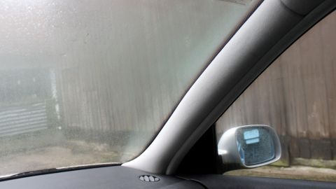 Beträchtliche Feuchtigkeit ist am Fenster im Auto sichtbar, während der Fahrer in einer geschlossenen Umgebung parkt.