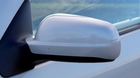 Ein blinkerfreier Rückspiegel ist an der Seite eines Autos montiert und reflektiert die Umgebung bei Tageslicht.