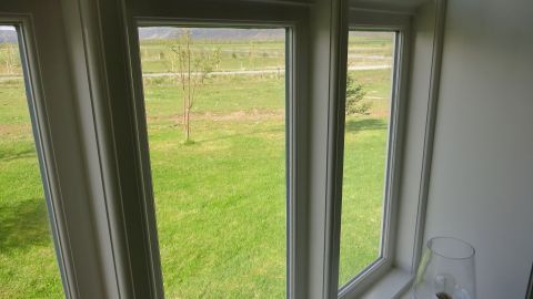 Saubere Fenster im Innenraum lassen Licht herein, während die grüne Wiese draußen eine natürliche Kulisse bildet.