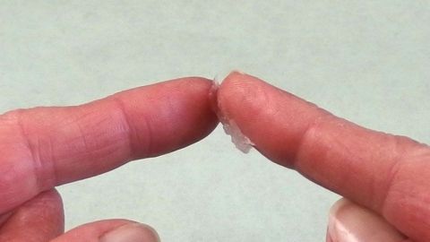 Sekundenkleber an den Fingern kann man mit Vaseline entfernen. Zwei Finger sind aneinander geklebt, während Vaseline zur Entfernung des Sekundenklebers verwendet wird.